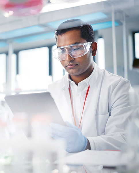 A man with dark hair works in a laboratory and is looking at a tablet. (photo)